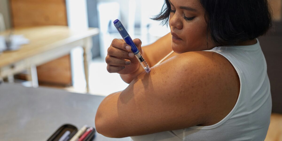A person using an injectable GLP-1 medication pen for diabetes and obesity treatment